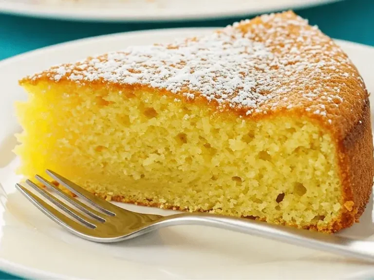 Gâteau au lait doré et moelleux sur une table en bois, avec une part découpée révélant une texture légère et fondante.